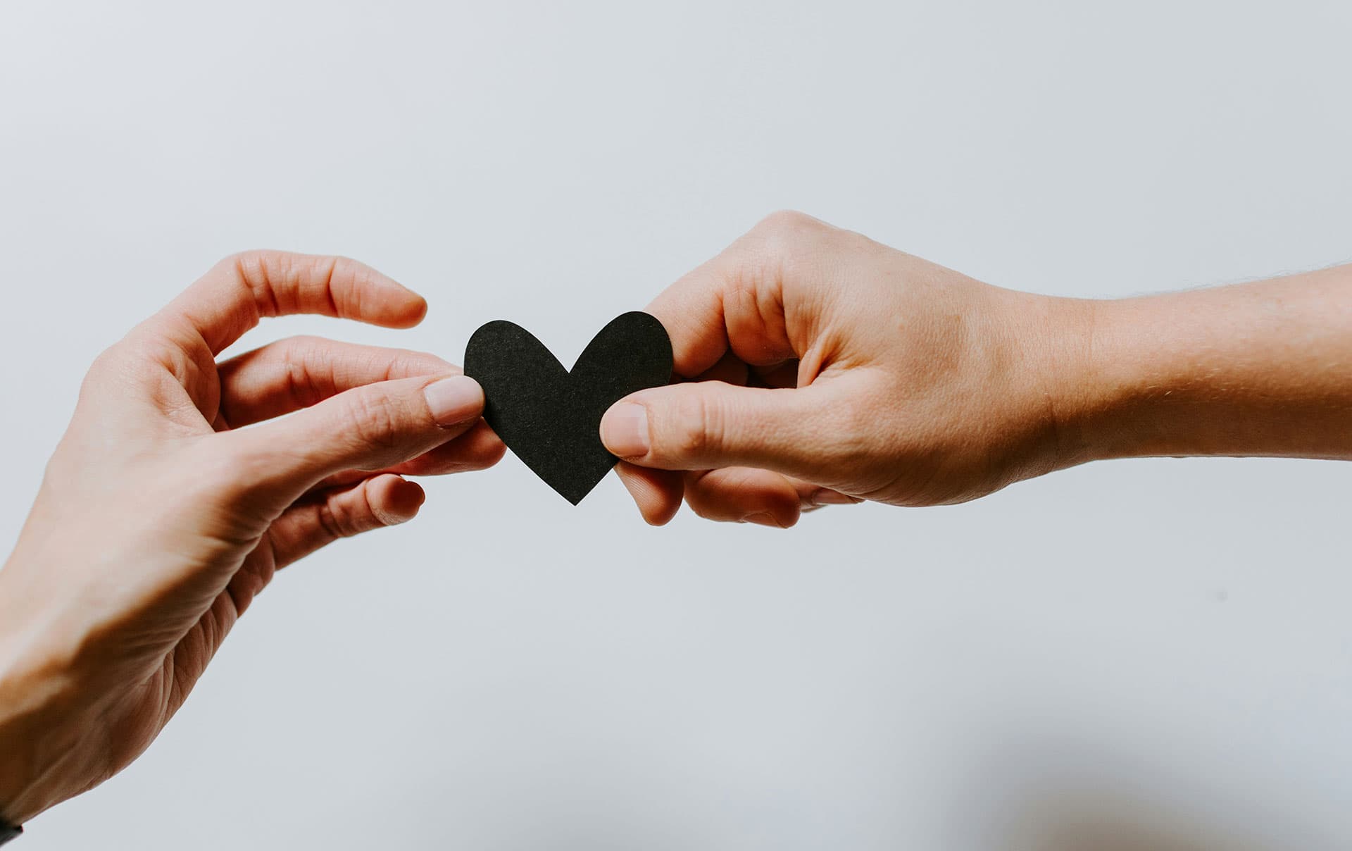 two-hands-sharing-a-paper-heart